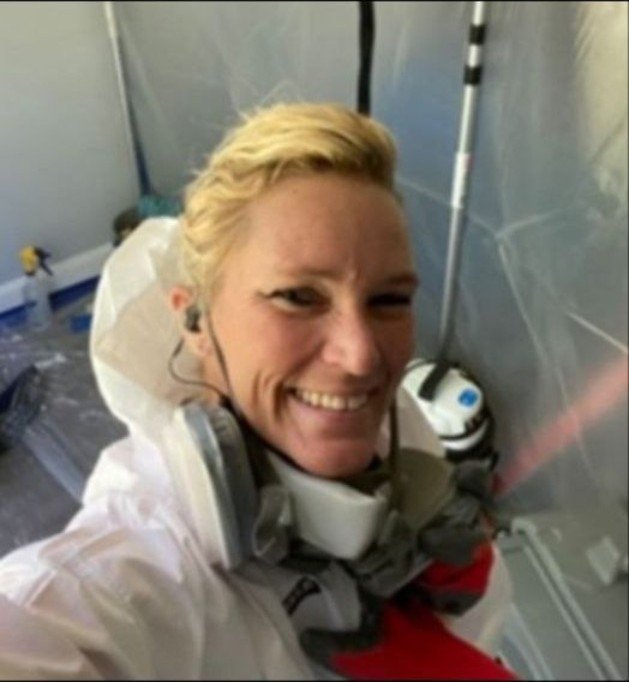 Tanith McCormick smiling while wearing protective equipment and a respirator inside an active containment work area